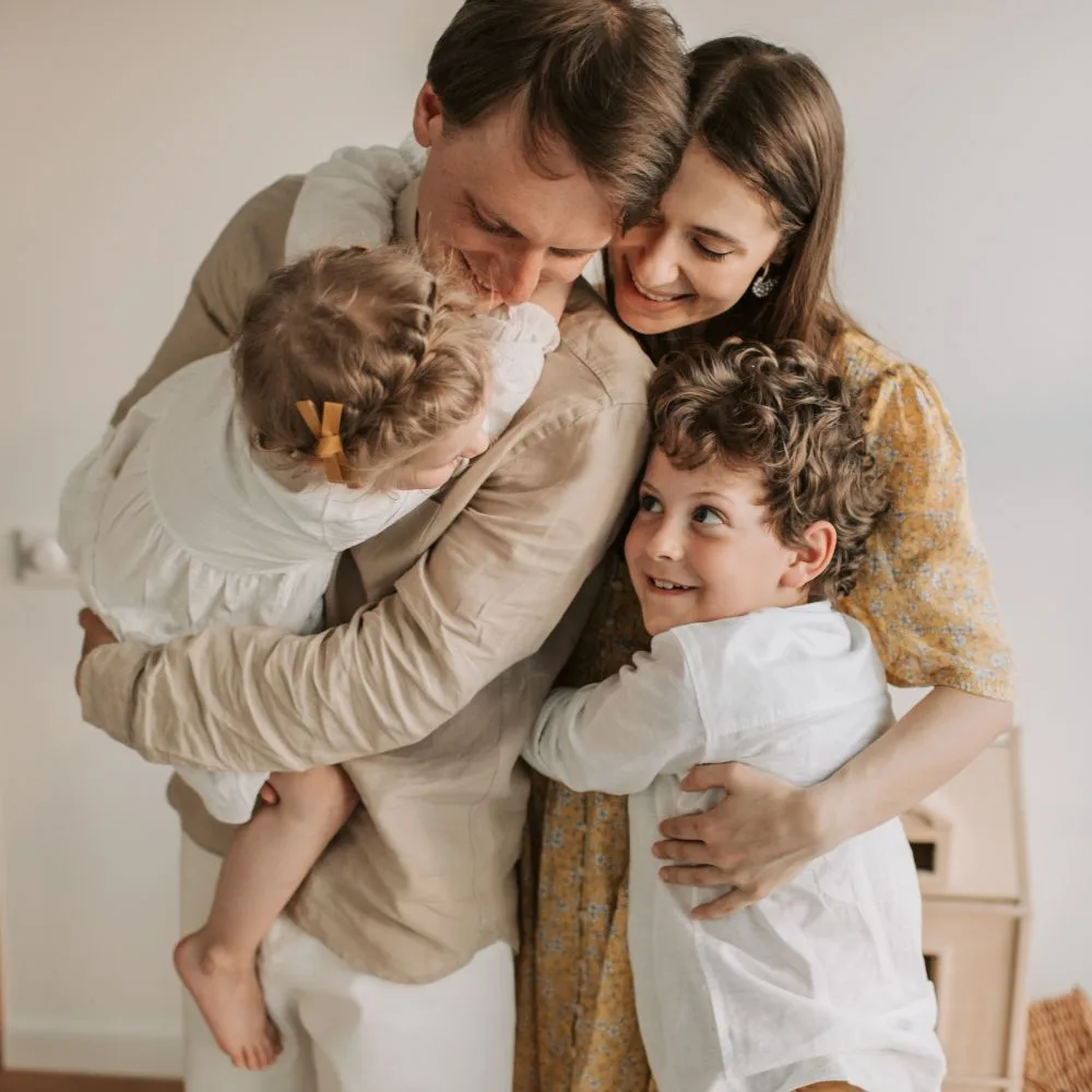 family of mother, father and two children, in a group hug