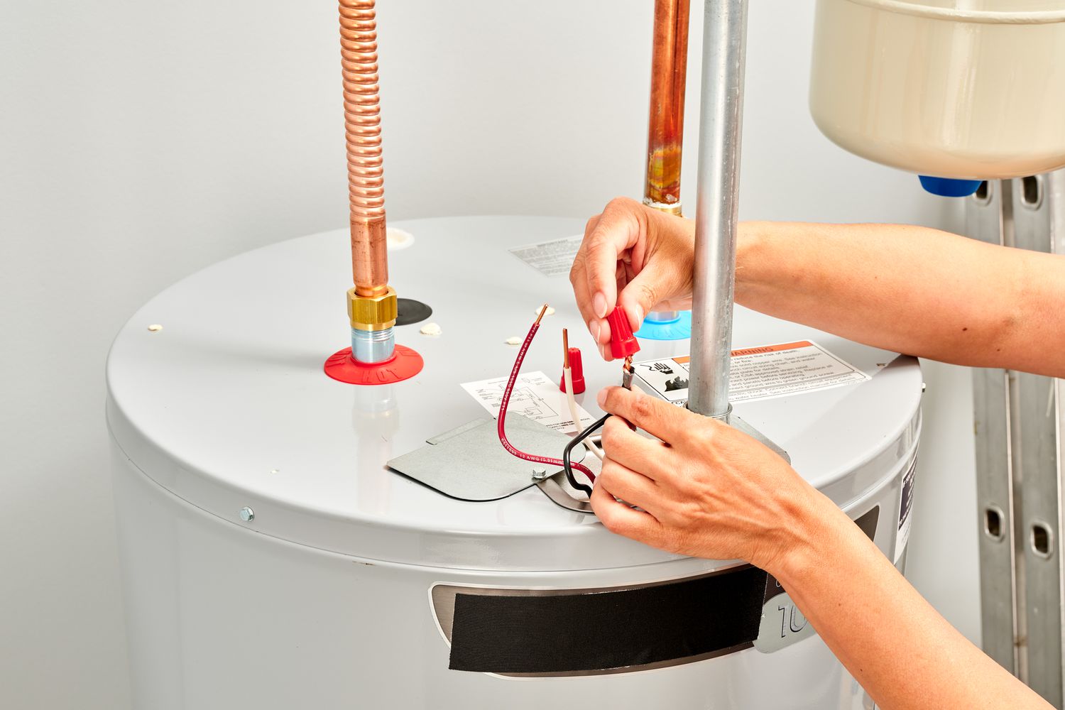 two hands working on electric water heater wiring