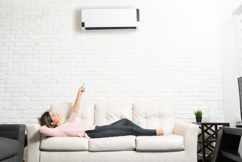 woman laying on a couch underneath a mini split HVAC unit
