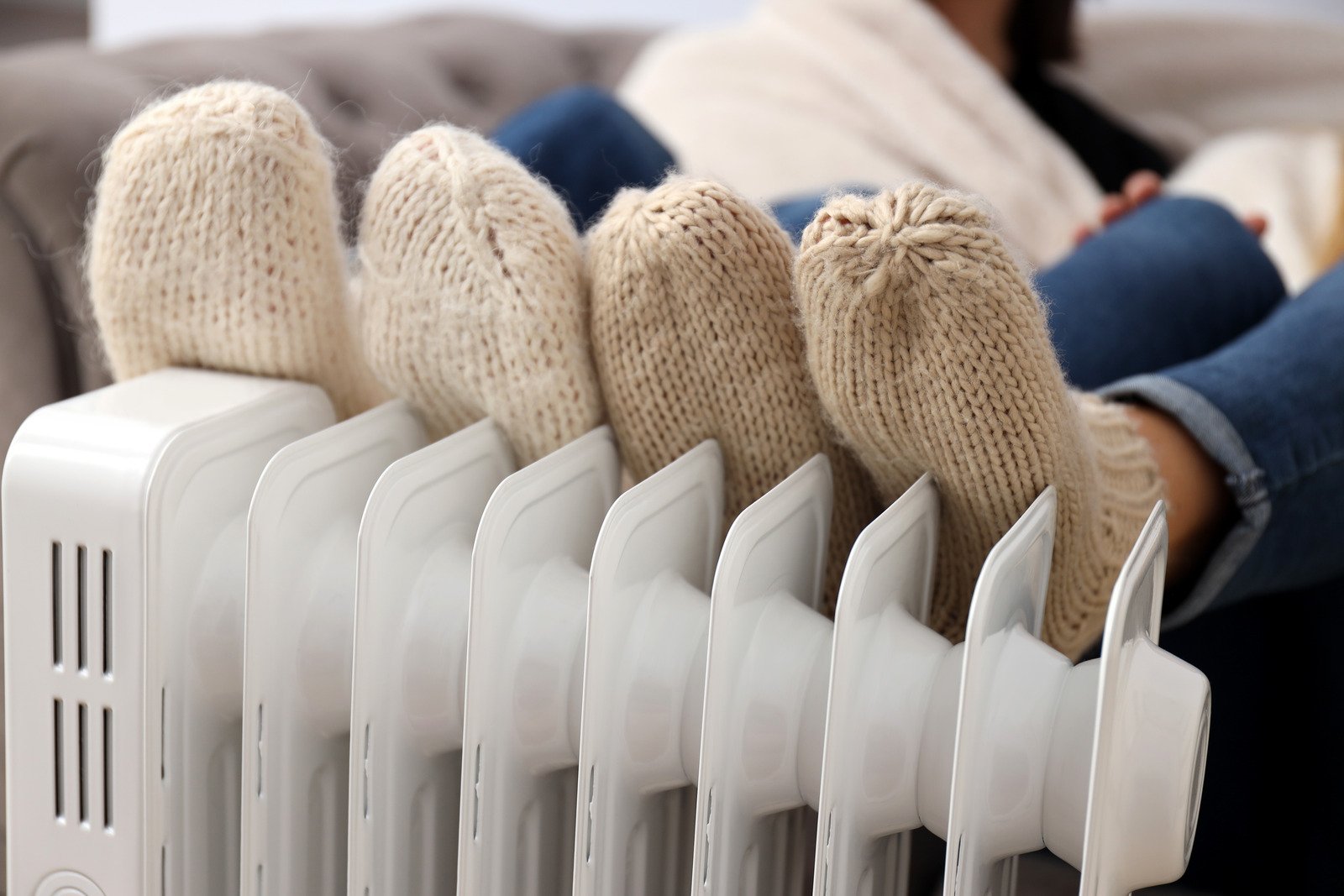 two pairs of feet in socks snuggled up against a heating radiator system in a home