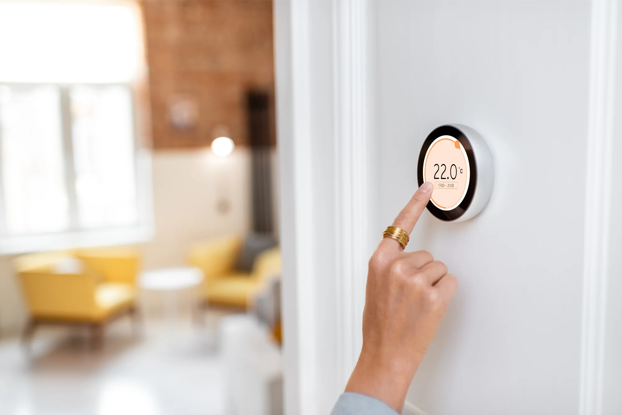 adjusting a digital thermostat on a white wall, set to 22°C