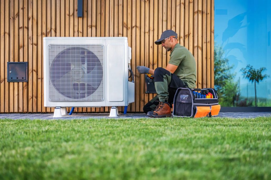 a technician is servicing an air conditioning unit located beside a modern home