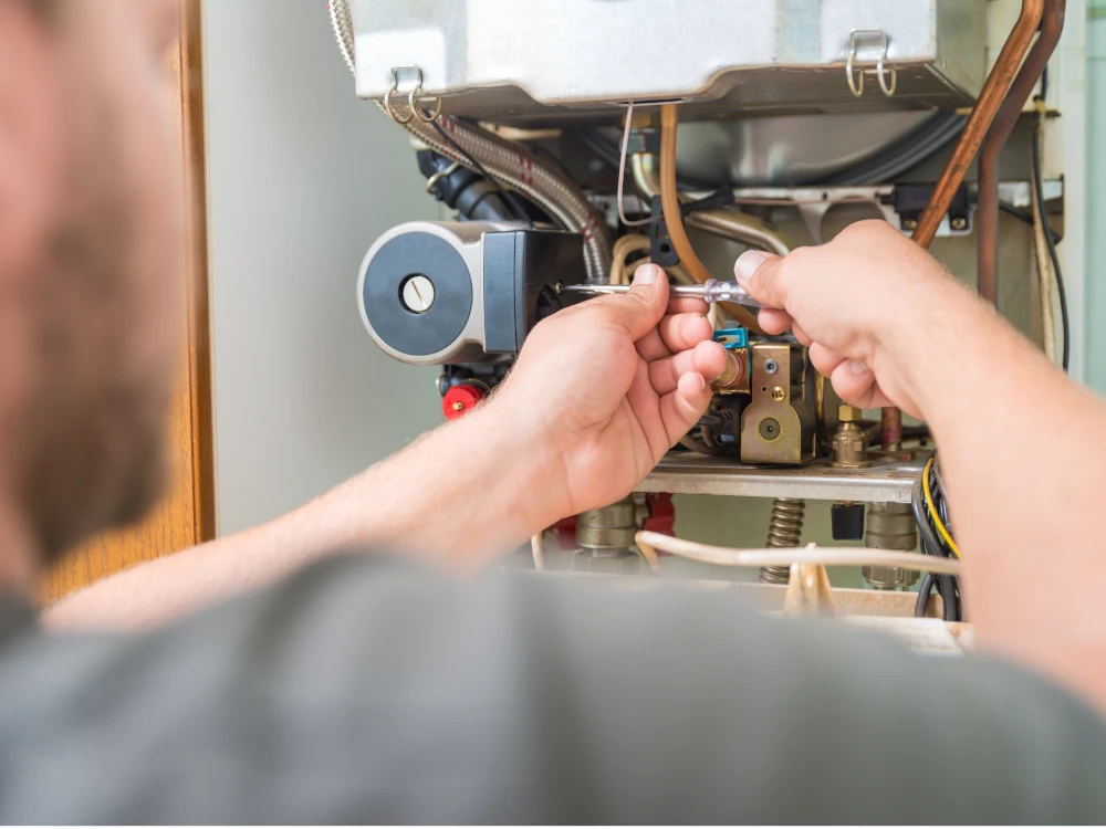 Technician uses a wrench to repair an exposed water heater, focusing on pipes and valves in a detailed, hands-on maintenance scene.